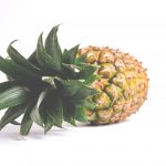 A fresh and ripe pineapple laying on its side with crown intact.