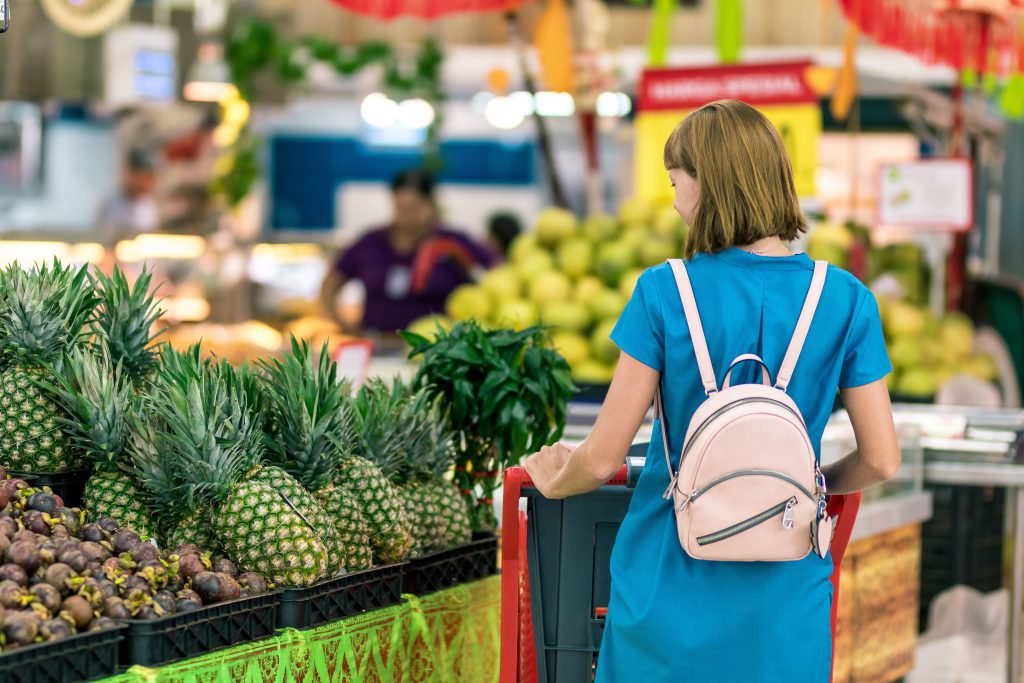 a woman taking a look through some pineapples in a supermarket