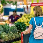 a woman taking a look through some pineapples in a supermarket