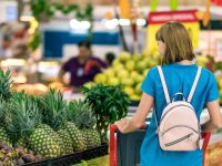 a woman taking a look through some pineapples in a supermarket