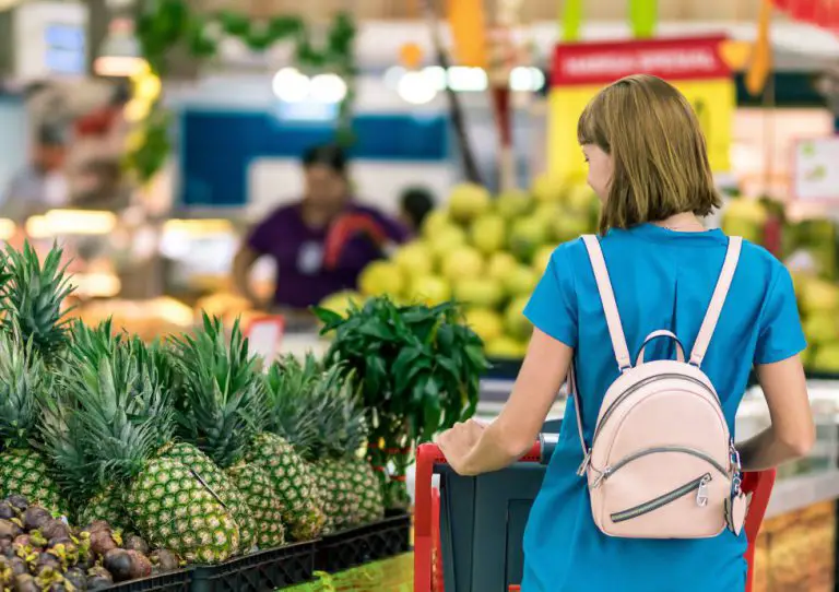 a woman taking a look through some pineapples in a supermarket