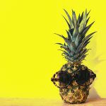 sunglasses on pineapple on yellow background