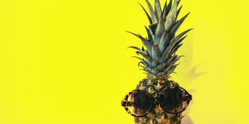 sunglasses on pineapple on yellow background