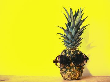 sunglasses on pineapple on yellow background