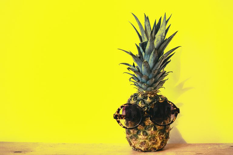 sunglasses on pineapple on yellow background